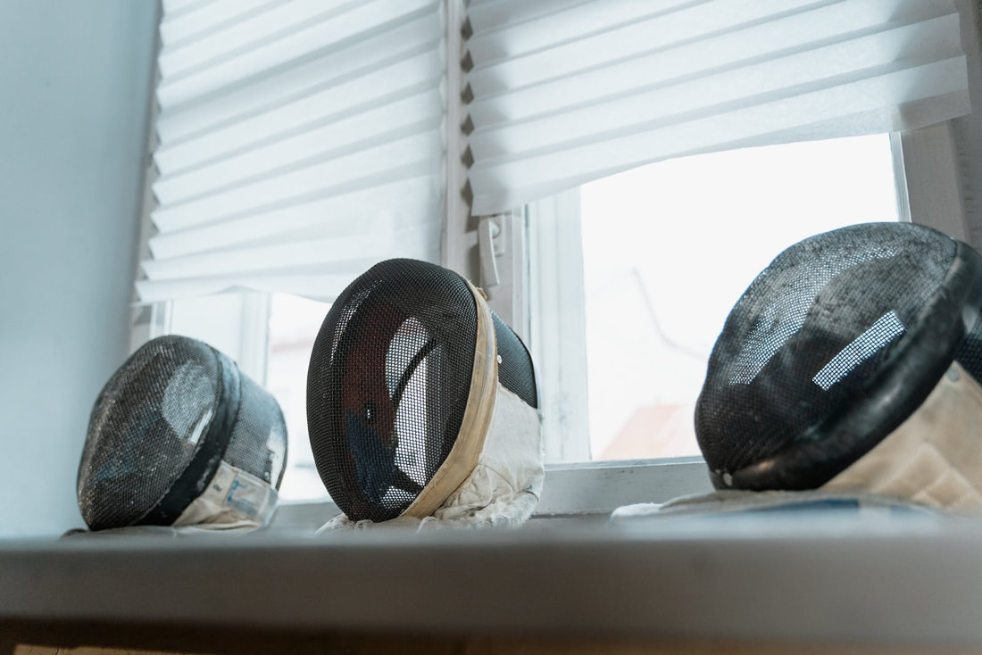 three masks on window ledge with half drawn window shades behind 
