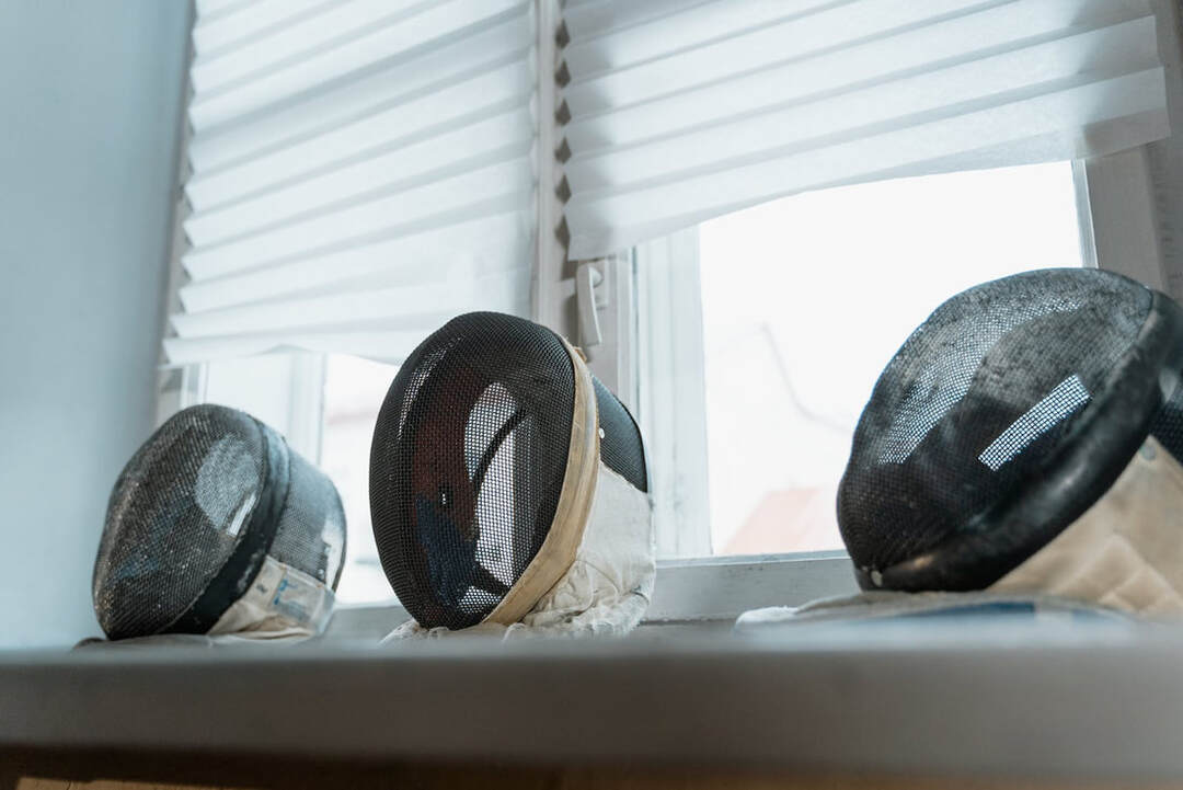 three masks on window ledge with half drawn window shades behind 